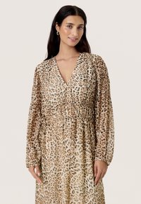 Leopardmønstret kjole i let, gennemsigtig stof. Har en V-udskæring, elastisk talje og lange ærmer med samlede manchetter.