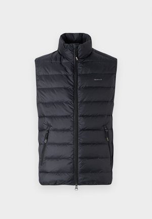 Gevoerde zwarte mouwloze vest met hoge kraag, frontrits en twee zijzakken. Heeft een subtiele merklogo op de borst.