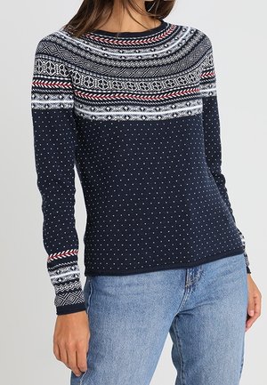 Maglione blu navy con pois bianchi, caratterizzato da un giromanica a fantasia in rosso, bianco e nero. Maniche lunghe con polsini a fantasia.