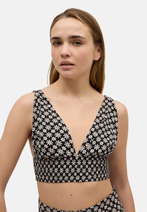 Top corto negro con patrón de margaritas blancas, diseño de escote en V profundo y banda fruncida. Presenta tirantes anchos y una silueta ajustada.