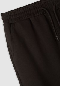 Czarne dresowe spodnie wykonane z miękkiej bawełny. Posiadają elastyczny pas ze sznurkiem, boczne kieszenie oraz teksturowane wykończenie materiału.