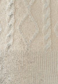 Helle beige gestrickte Stoff mit einem strukturierten Diamant- und Kabelmuster, mit dezenten metallischen Akzenten und einem gerippten unteren Rand.