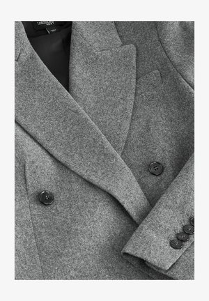 Sivý vlnený blejzer s dvojitým zapínaním, s výstrihom a čiernymi gombíkmi, vyrobený z textúrovanej látky. Má priliehavý strih a čisté línie.