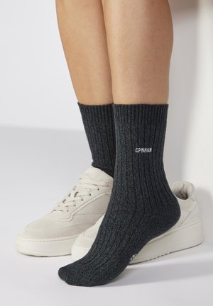 Grey ribbed socks with a textured pattern, featuring white text "CPN H6N" near the top, paired with beige sneakers.