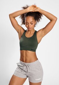 Zielony stanik sportowy o prążkowanej fakturze z akcentem logo. Połączony z jasnoszarymi szortami ze sznurkiem z białym logo.