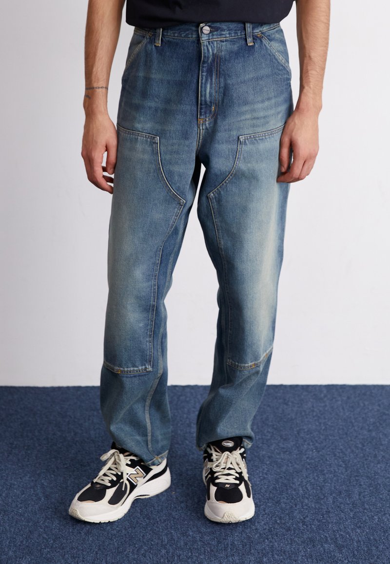Lys blå denim bukser med en avslappet passform, falmede områder og frontlommer. Kombinert med svarte og hvite trening sneakers.