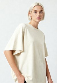 Beige pārāk liels kokvilnas T-krekls ar īsām piedurknēm, apaļu kakla izgriezumu un mīkstu tekstūru, ar brīvu piegriezumu un minimālisma dizainu.