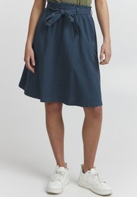 Jupe en denim A-line bleu foncé avec une taille élastique et un lien ajustable. Dispose d'une poche latérale et d'un détail de couture propre.