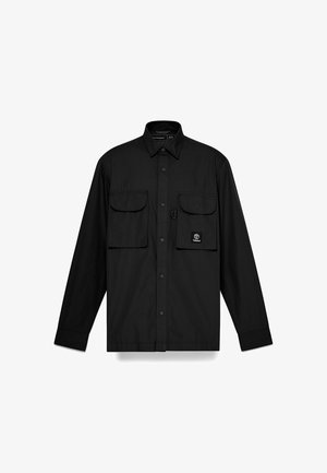 Chemise noire à manches longues en tissu lisse, dotée de deux poches sur la poitrine et d'un petit logo sur la poche gauche. Fermeture à boutons sur le devant.