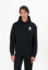 Sweatshirt preto com capuz feito de um tecido suave, apresentando um bolso frontal e uma impressão gráfica com texto na área do peito esquerdo.