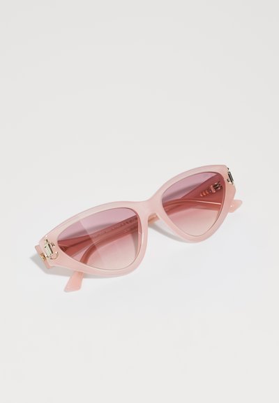Cat-eye sunglasses with a translucent pink frame, gradient pink lenses, and gold hardware accents on the outer side of the frame.