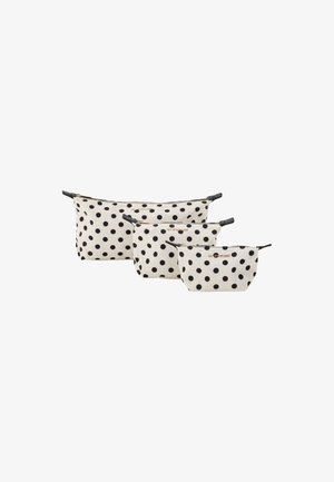 Trois pochettes à pois crème avec des pois noirs, fabriquées en tissu avec des fermetures éclair et des accents noirs, de tailles variées.