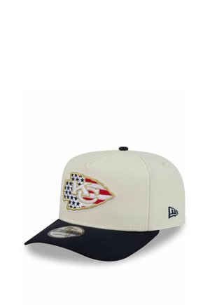 Off-white baseball cap with black brim featuring Kansas City Chiefs logo filled with American flag stars and stripes on front panel.