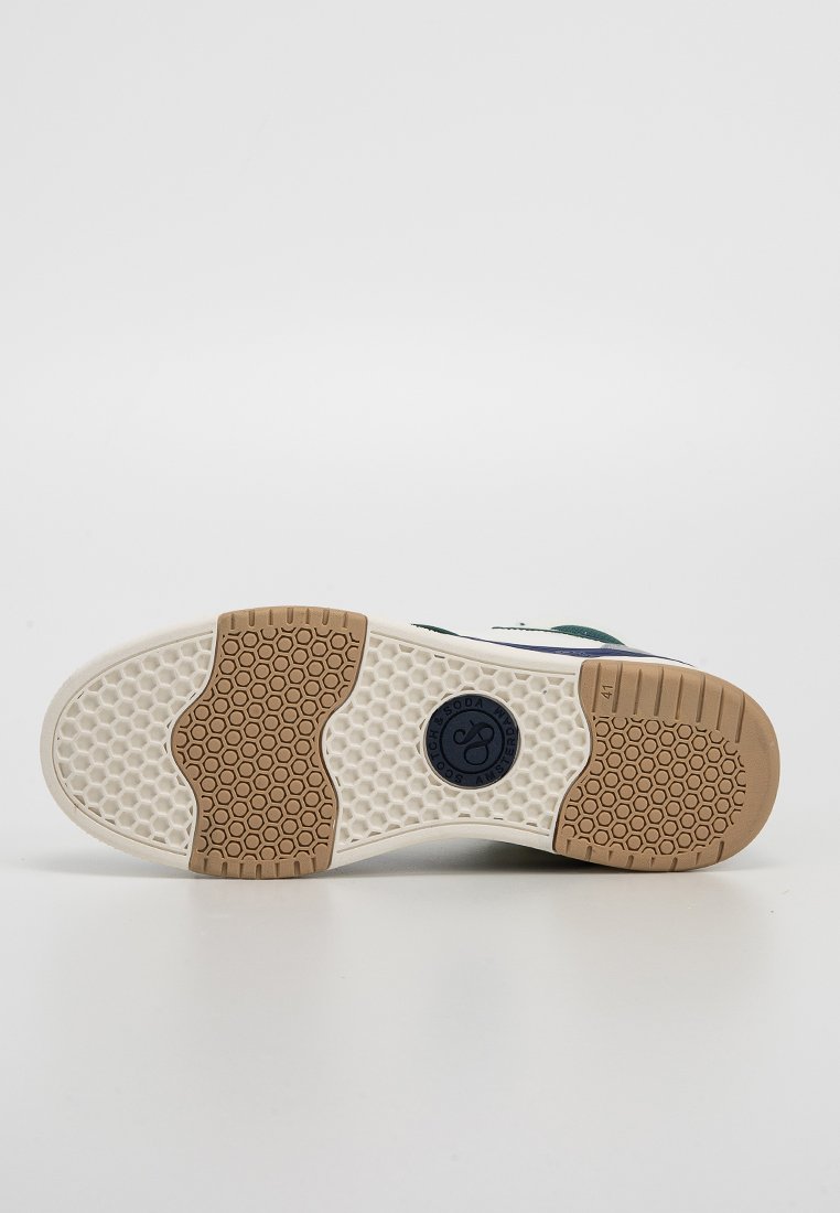 Schuhsohle aus Gummimaterial, flaches Design, beiger Zwischensohle, hexagonale Textur, kreisförmiges Logodetail und dunkelgrüne Akzente an der Oberseite.