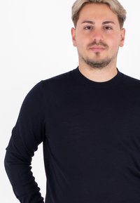 Maglione a maniche lunghe blu navy in tessuto a coste, design a girocollo, silhouette aderente, texture liscia senza motivi o dettagli visibili.