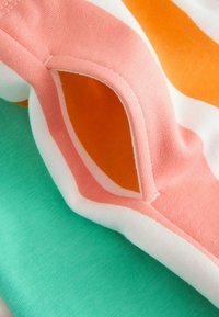 Opgevouwen stof met groene, witte, oranje en roze strepen, close-up weergegeven om de textuur en naaddetails te benadrukken.