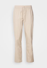 Beige bukser med en afslappet pasform, elastisk talje og snor. Glat tekstur, let tapered ben, og ingen synlige mønstre eller hardware.
