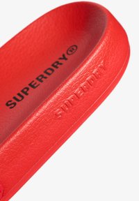 Rød, struktureret indersål med "SUPERDRY" prægget langs kanten. Kontureret form designet til komfort og støtte.