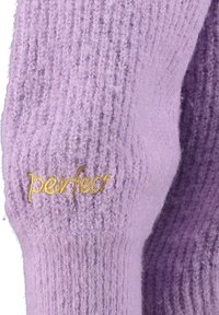 Fliederfarbener Strickärmel mit gelb besticktem Wort "perfect" nahe der Manschette, zeigt weiches, strukturiertes Gewebe.