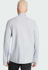 Lichtgrijze lange mouwen sportieve top met een kraag, een gladde textuur en een aangesloten ontwerp. Zijsplitten aan de zoom verbeteren de bewegingsvrijheid.