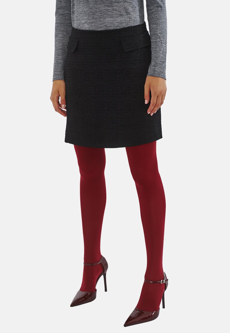 Czarna mini spódniczka z tweedu z dwiema przednimi kieszeniami, zestawiona z czerwonymi kryjącymi rajstopami i burgundowymi szpilkami. Widoczna jest także szara bluzka z długim rękawem.