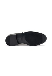 Sole di scarpa in gomma nera con superficie testurizzata, caratterizzata da un'area della punta liscia e scanalature per trazione. Design semplice, senza branding visibile.