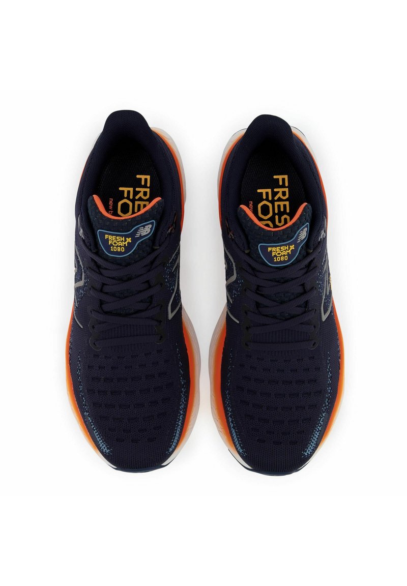 Zapatillas deportivas de color azul oscuro con parte superior de malla, acentos en naranja brillante, suela texturizada y marca en la lengüeta. Cuentan con cierre de cordones y amortiguación.