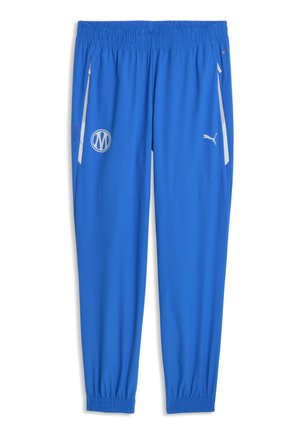 Niebieskie spodnie sportowe z elastycznym pasem i mankietami, boczne kieszenie na zamek z białym obszyciem, logo Puma na prawej udzie oraz okrągła naszywka na lewym udzie.