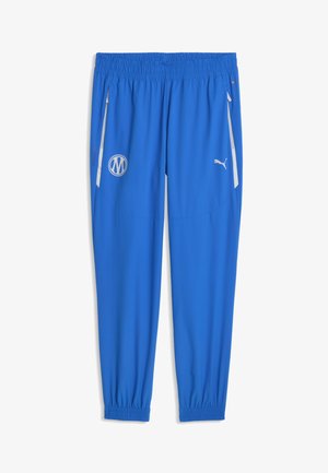 Niebieskie spodnie sportowe z elastycznym pasem i mankietami, boczne kieszenie na zamek z białym obszyciem, logo Puma na prawej udzie oraz okrągła naszywka na lewym udzie.