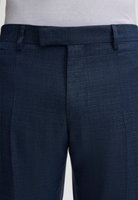 Marineblau maßgeschneiderte Hose mit strukturiertem Finish, mit flachem vorne, Gürtelschlaufen und einem glatten Bund. Schlichtes Design, keine Muster.
