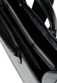 Juodas odinis maišas su užtraukiama kišenė, lygiu paviršiumi ir keliomis kišenėmis organisationui. Minimalistinis dizainas, tvirti rankenai.