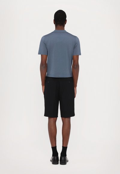 Grått polo skjorte med korte ermer, sammen med svarte knelange shorts. Teksturert stoff; minimalistisk design uten synlige mønstre.