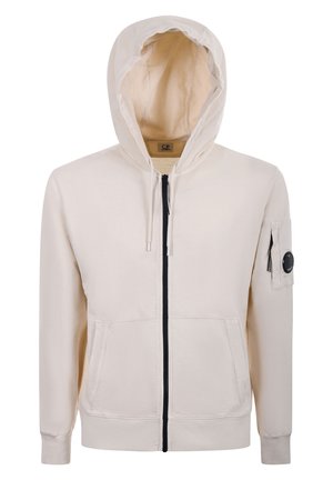 Felpa con cappuccio beige chiaro con zip, tasche frontali, cappuccio con coulisse e piccola tasca con zip con dettaglio rotondo nero sulla manica sinistra.