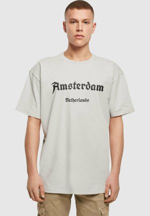 Hellgraues, übergroßes T-Shirt mit "Amsterdam" und "Niederlande" in schwarzer gotischer Schrift bedruckt. Hergestellt aus weichem Baumwollmischmaterial.