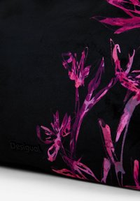 Czarny materiał z wyraźnym kwiatowym wzorem w odcieniach różu i fioletu. Dyskretny wytłoczony logo "Desigual". Gładka tekstura.