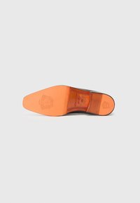 Suola di scarpa in pelle marrone con una forma curva. Presenta un fondo arancione, un'impronta del logo e dettagli testurizzati lungo i bordi.