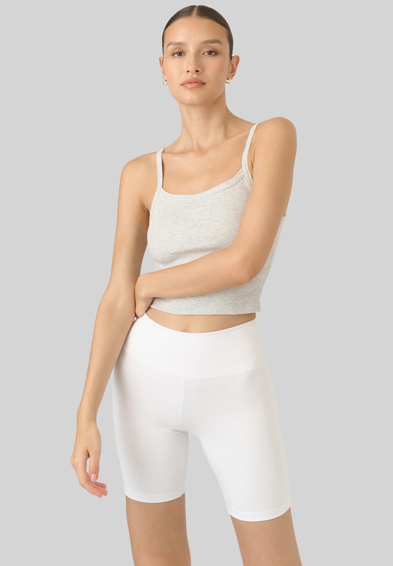 Szary prążkowany krótki top na ramiączkach z cienkimi paskami, w zestawie z białymi szortami rowerowymi o wysokim stanie. Gładka faktura i dopasowany krój.