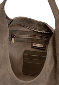Grijze suède handtas interieur met een ritsvak en een kaartsleuf. Kenmerkt een gladde stofvoering en een merklabel.