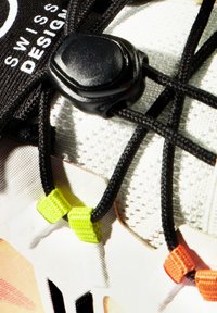 Białe buty teksturowane z czarnymi sznurowadłami i zamkiem. Posiadają żywe żółte i pomarańczowe akcenty w pobliżu sznurowadeł.