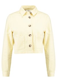 Chaqueta de denim recortada de color amarillo claro con mangas largas, cuello, cierre frontal de botones y dos bolsillos cuadrados en la parte delantera.