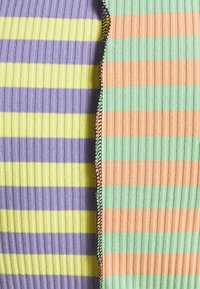 Ribbed fabric with alternating stripes in purple, yellow, green, and orange. Black stitching along the seam. Texture is soft and stretchable.