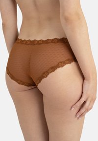 Sous-vêtements marron bordés de dentelle avec un motif à pois, présentant une texture lisse et une coupe taille basse, vus de profil.