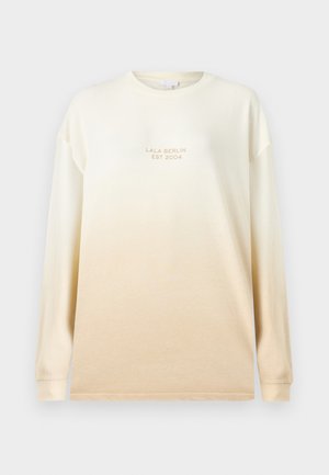 Hosszú ujjú, krém színű ing, amelynek színe fokozatosan sötétebb bézsbe megy át. Kerek nyakkivágású, és dombornyomott felirat található rajta: "LALA BERLIN EST 2004."