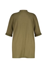 T-shirt oversize vert olive en tissu doux, avec un col rond, des manches courtes retroussées et un ourlet droit.