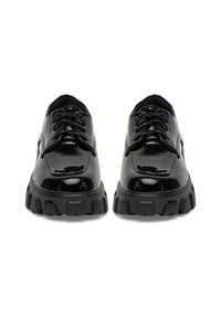 Mustad lakknahast kingad ümarate ninadega, millel on paksud, jämedad mustad tallad ja traditsiooniline nööritav disain.