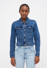 Denim jakna v temno modri barvi, oprijetega kroja z dvema žepoma na prsih, oranžnimi gumbi in dolgimi rokavi; skrajšana dolžina z rahlo raztrganim robom.