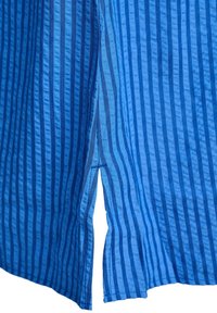 Niebieska tkanina z pionowymi ciemnoniebieskimi paskami oraz małym rozcięciem po boku u dołu odzieży.