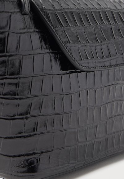 Μαύρη δερμάτινη γυναικεία τσάντα χειρός με γυαλιστερή υφή κροκοδείλου και κλείσιμο με πτερύγιο που έχει εμφανείς ραφές κατά μήκος των άκρων.
