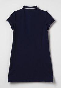 Granatowa sukienka polo z krótkimi rękawami i żebrowanym kołnierzykiem. Posiada biały pasek na kołnierzyku. Gładki materiał bawełniany.