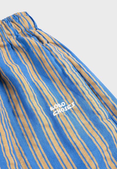 Tissu rayé bleu et beige avec une ceinture élastique et un texte brodé en blanc indiquant "Moto Explorer" sur le vêtement.